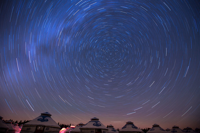 拿着打开手电筒的手机,不小心从镜头前走过,结果在星空前划出一道闪亮